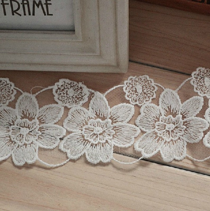 May include: White lace trim with a floral design. The lace is delicate and intricate, with small flowers and leaves.