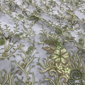K&ouml;nnte beinhalten: Gr&uuml;ner, gestickter Blumenspitzenstoff mit einem zarten Muster aus Bl&auml;ttern und Bl&uuml;ten. Die Spitze ist durchsichtig und hat eine weiche, flie&szlig;ende Textur.
