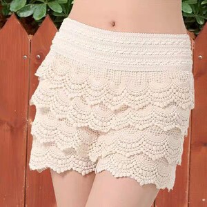 May include: White crochet shorts with multiple layers of scalloped lace trim.