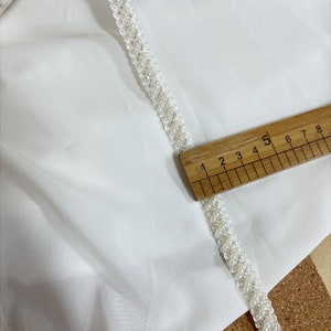 May include: White beaded trim with a ruler measuring 5 inches long.
