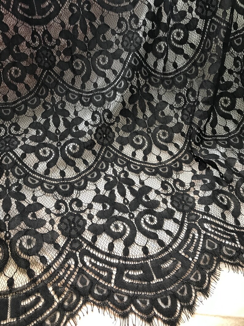 Puede incluir: Tela de encaje negra con un delicado patr&oacute;n floral. El encaje tiene un borde festoneado.