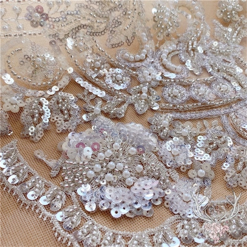 Pu&ograve; includere: Tessuto di pizzo bianco con perline e paillettes con un motivo floreale. Il tessuto &egrave; trasparente e ha una texture delicata.
