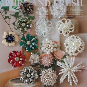Peut inclure: Une collection d'embellissements floraux décoratifs de différentes couleurs et designs. L'assortiment comprend des broches de fleurs perlées, à paillettes et en strass, parfaites pour l'artisanat ou pour ajouter du style aux vêtements. Le fond présente le texte "PUR AND FRESH".