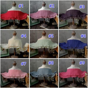 May include: Nine different colored pleated fabric collars displayed on dress forms. Colors include red, pink, purple, cream, mint green, blue, and rose. Each collar is labeled with a number from 1 to 9.