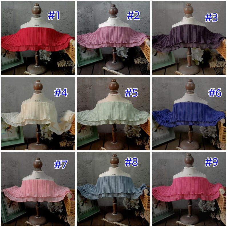 May include: Nine different colored pleated fabric collars displayed on dress forms. Colors include red, pink, purple, cream, mint green, blue, and rose. Each collar is labeled with a number from 1 to 9.