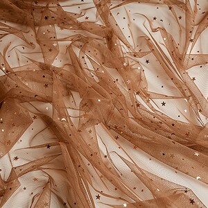 May include: Brown tulle fabric with gold glitter stars. The fabric is sheer and has a delicate texture.