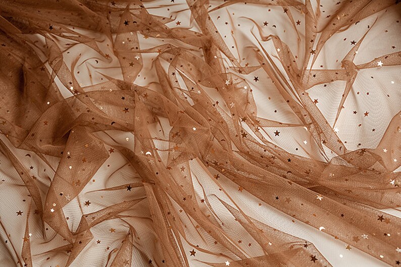 May include: Brown tulle fabric with gold glitter stars. The fabric is sheer and has a delicate texture.