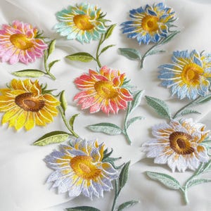 May include: Embroidered sunflower patches in various colors, including pink, yellow, blue, and white. Each patch features a detailed design with green stems and leaves, perfect for adding a floral touch to clothing or crafts.