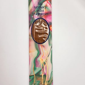 May include: A package of Atma Nagchampa incense sticks from The Mother's India Fragrances. The packaging features a colorful design with pink, green, and gold accents, and a gold lotus flower. The incense sticks are visible through an oval window.