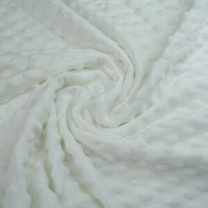 May include: White textured fabric with a soft, crinkled appearance. The fabric is folded and draped, creating a swirling pattern.