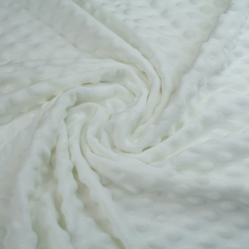 May include: White textured fabric with a soft, crinkled appearance. The fabric is folded and draped, creating a swirling pattern.