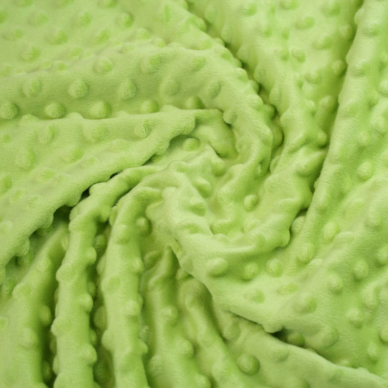 May include: A close-up of a soft, green fabric with a textured, bubble-like pattern. The fabric is wrinkled and folded, showing the texture and colour.