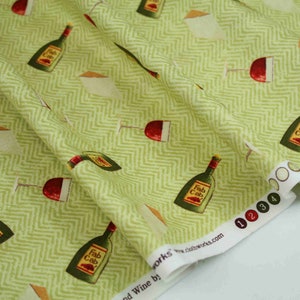 May include: Green fabric with a white chevron pattern featuring a repeating design of wine bottles labelled "Fab Cab" and wine glasses. The fabric has a white edge with black numbers 1, 2, 3, and 4.
