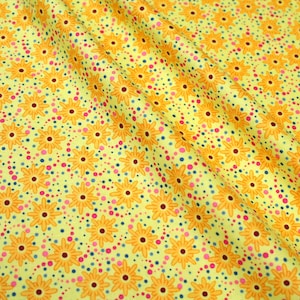 May include: Yellow fabric with a repeating pattern of orange flowers and pink and blue dots.