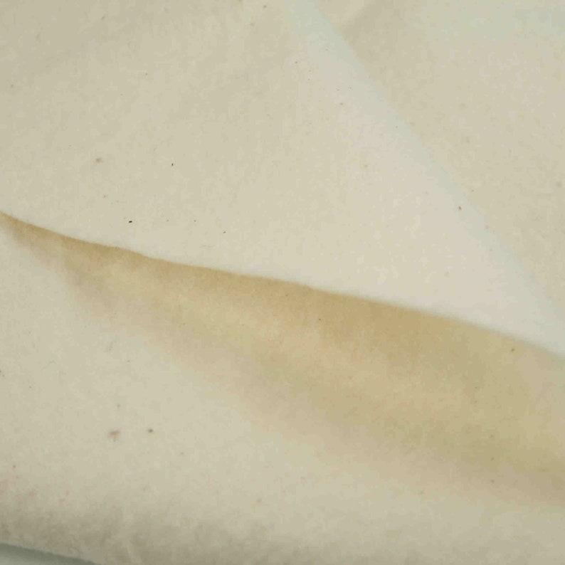 May include: Close-up of a white, textured fabric. The fabric is folded in half, showing the underside of the fabric.