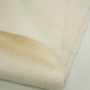 May include: A close-up of a white, soft, and textured fabric. The fabric is folded in half, revealing the soft, fluffy texture.