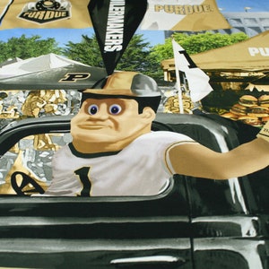 May include: A cartoon mascot wearing a white jersey with a gold number one, a gold helmet, and a gold and black baseball cap. The mascot is driving a black truck with a gold steering wheel. The background is a collage of images with the word "Purdue" and the text "Boilermakers".