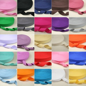 Può includere: Una collezione di 25 rotoli di fettuccia di cotone in vari colori, tra cui rosa, verde, viola, bianco, rosso, arancione, blu e giallo. La fettuccia è larga circa 2,5 cm ed è perfetta per l'artigianato, la cucitura e altri progetti fai-da-te.