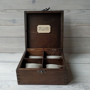 May include: A dark brown wooden box with a hinged lid and a small metal latch. The box has six compartments lined with beige fabric. The lid has a small wooden plaque with the text "This is a place for your text."