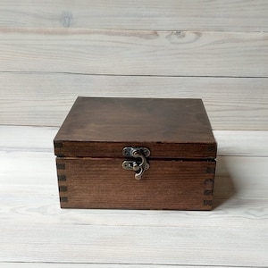 May include: A dark brown wooden box with a hinged lid and a brass latch. The box is made of solid wood and has a natural finish.