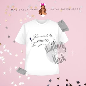 May include: White t-shirt with black text that reads "Powered by prayers & pixie dust" with a black and blue wand graphic. The text "Magically Made Merch" is in a white circle with a black outline.
