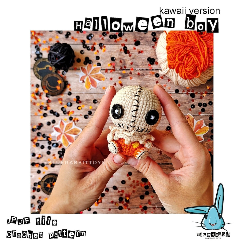 May include: A crocheted Halloween boy doll with a stitched face, black button eyes, and orange pants. The doll is being held by a person's hands against a background of fall-themed confetti.
