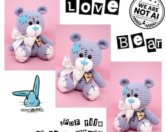 Puede incluir: Un oso de peluche de ganchillo de color morado claro con hocico blanco, nariz bordada en azul, ojos de botón negros y una cinta blanca con patrones dorados. Presenta un parche azul en una oreja, un botón de corazón de madera y plantas blancas.