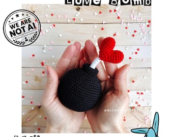 May include: A black crocheted sphere shaped like a bomb with a white fuse and a red crocheted heart at the end. The text LOVE BOMB is at the top, and the text .PDF file crochet pattern is at the bottom, with a WE ARE NOT AI stamp.