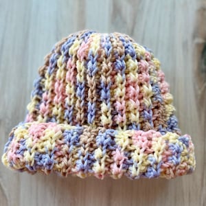 May include: A crocheted hat with stripes of pink, yellow, purple, and brown.