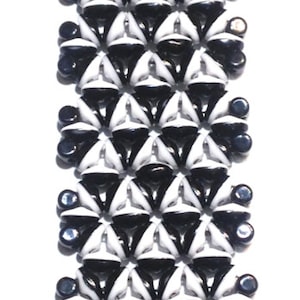 May include: Black and white beaded bracelet with a geometric pattern. The bracelet has silver metal clasps.