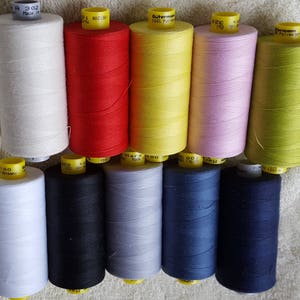 May include: Ten spools of thread in various colors, including white, red, yellow, pink, green, black, gray, and blue. The spools are labeled "Gutermann 100% Polyester" and "Made in Germany".