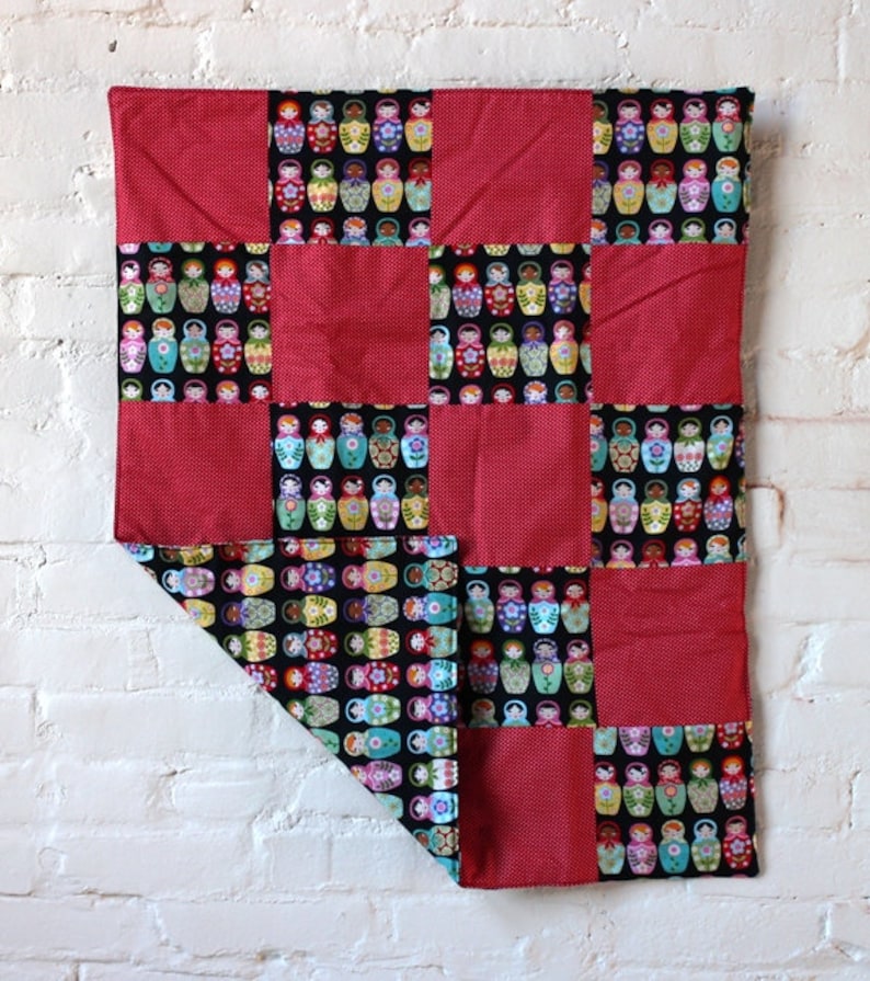 Hand made baby quilt with matryoshka doll motif juxtaposed to red and white polka dots.