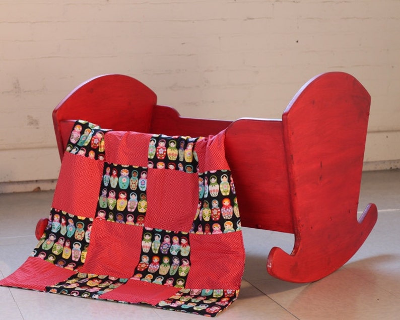 Hand made baby quilt with matryoshka doll motif juxtaposed to red and white polka dots.