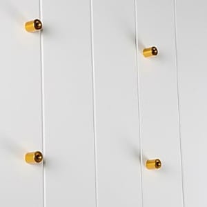 May include: Four gold-coloured metal knobs mounted on a white wall.