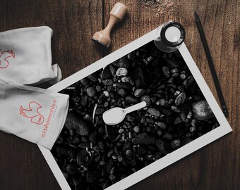 Foto della spiaggia di Santorini: ciottoli vulcanici neri, stampa artistica con pala bianca