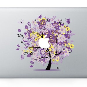 Op de afbeelding: Een laptop skin met een bloemenontwerp met een paarse en gele boom met vlinders. De boom is gestileerd en heeft een wit Apple-logo in het midden.