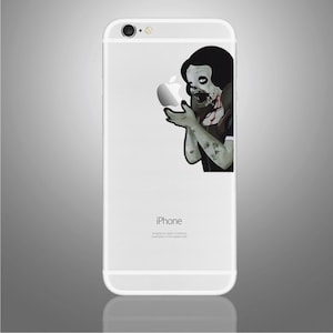 May include: A white iPhone case featuring a zombie Snow White sticker. The sticker depicts Snow White holding a red apple with blood dripping from her mouth. The text "iPhone" is printed on the case.