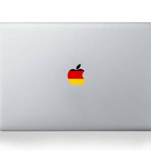 Könnte beinhalten: Ein silberner Laptop mit einem schwarzen, gelben und roten Apple-Logo-Aufkleber auf dem Deckel.