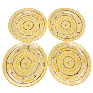 Może przedstawiać: Cztery żółte ceramiczne talerze z kwiatowym wzorem. Każdy talerz ma centralny motyw kwiatowy, otoczony koncentrycznymi okręgami z małych białych kwiatów i brązowych akcentów. Talerze są ułożone na białym tle.