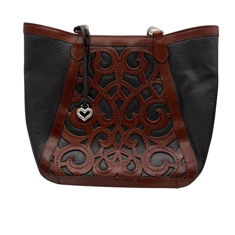 May include: Black and brown leather tote bag with a decorative cut-out design. The bag features a heart-shaped charm and brown leather trim. The tote has a structured shape and a top handle.
