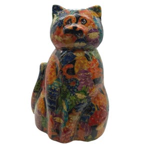 May include: A cat figurine featuring a vibrant, multi-coloured surface pattern composed of numerous smaller cat illustrations in shades of orange, blue, purple, and yellow, with a glossy finish and a tail visible on the left side of the body.