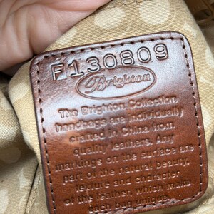 May include: A close-up of a brown leather tag with the text "F130809 Brighton". The tag reads "The Brighton Collection handbags are individually crafted in China from quality leathers."