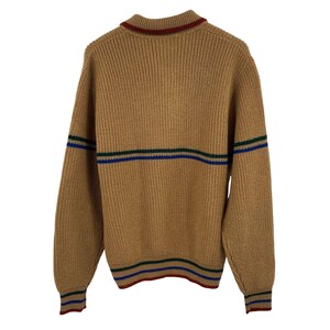 May include: A brown knitted sweater with green, blue, and red stripes around the neck, cuffs, and hem.