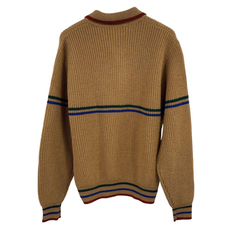 May include: A brown knitted sweater with green, blue, and red stripes around the neck, cuffs, and hem.