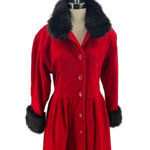 May include: A red coat with a black faux fur collar and cuffs. The coat has a button-up front and a fitted waist.