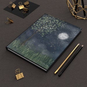 Peut inclure: Un journal à couverture rigide noire avec une illustration aquarelle d'un arbre avec des fleurs blanches et une lune dans un ciel nocturne. Le journal porte le texte "Stolen" sur la couverture.