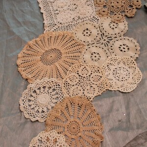 May include: A collection of crocheted doilies in various sizes and patterns, arranged in a cascading design on a light gray tablecloth.