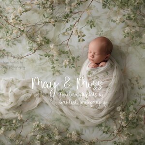 May include: A newborn baby wrapped in a soft, white blanket, nestled amidst a floral backdrop. The background features delicate branches with white flowers and green leaves. The text "May & Moss" is visible.