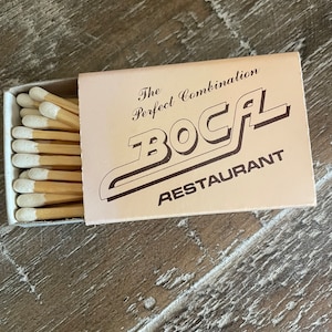 May include: A box of matches with white tips. The box is pink and has the text "The Perfect Combination" and "BOCAL RESTAURANT" printed on it.