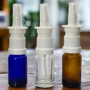 May include: Three glass spray bottles with white tops and clear plastic sprayers. The bottles are blue, clear, and brown.